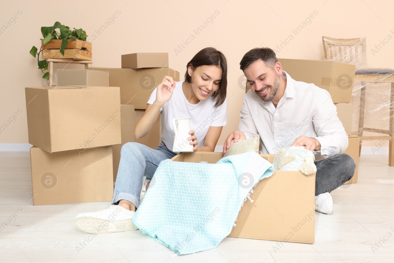 Photo of Happy couple unpacking box in new apartment. Moving day