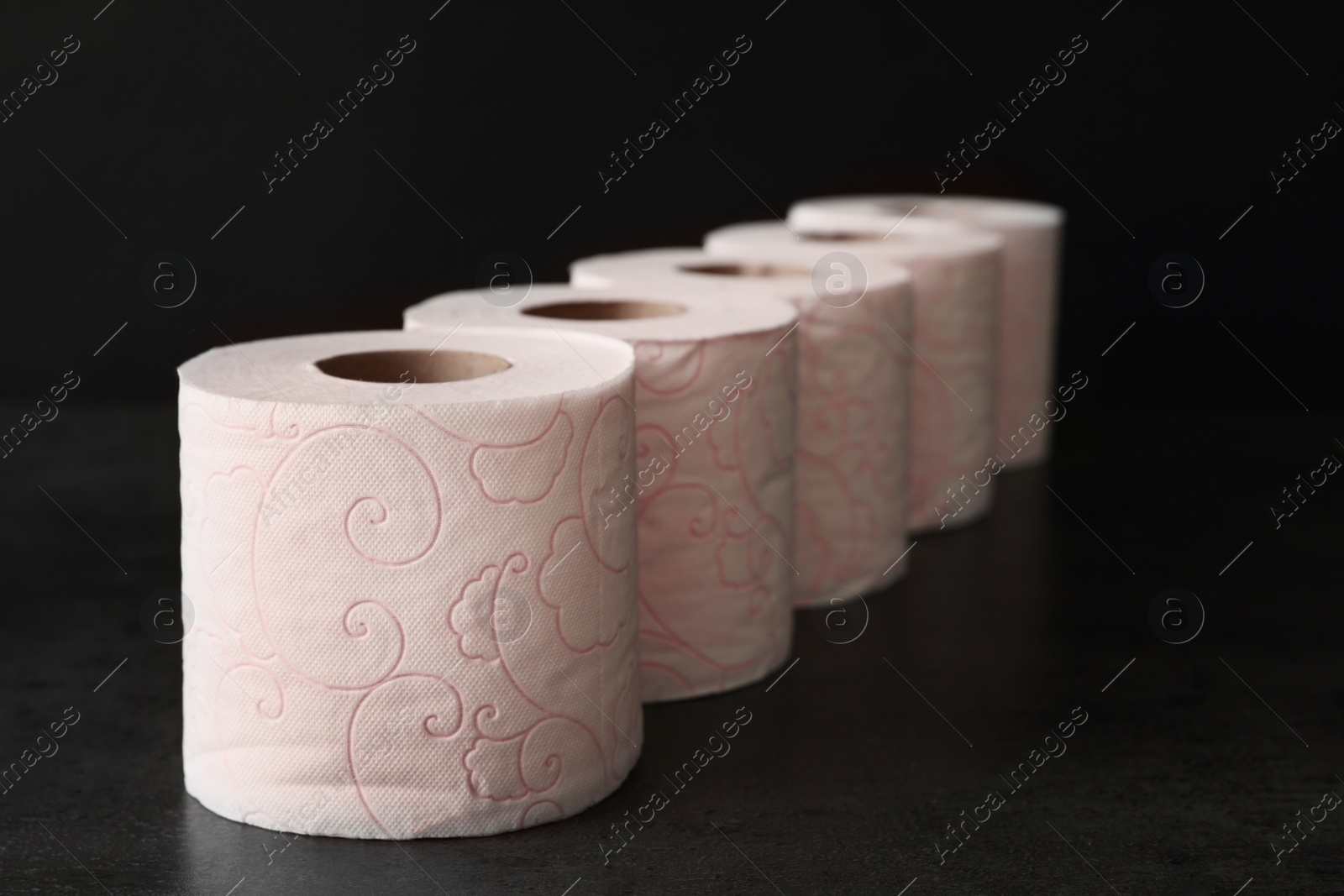 Photo of Row of toilet paper rolls on black background
