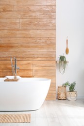 Photo of White tub and beautiful plants in bathroom, Interior design