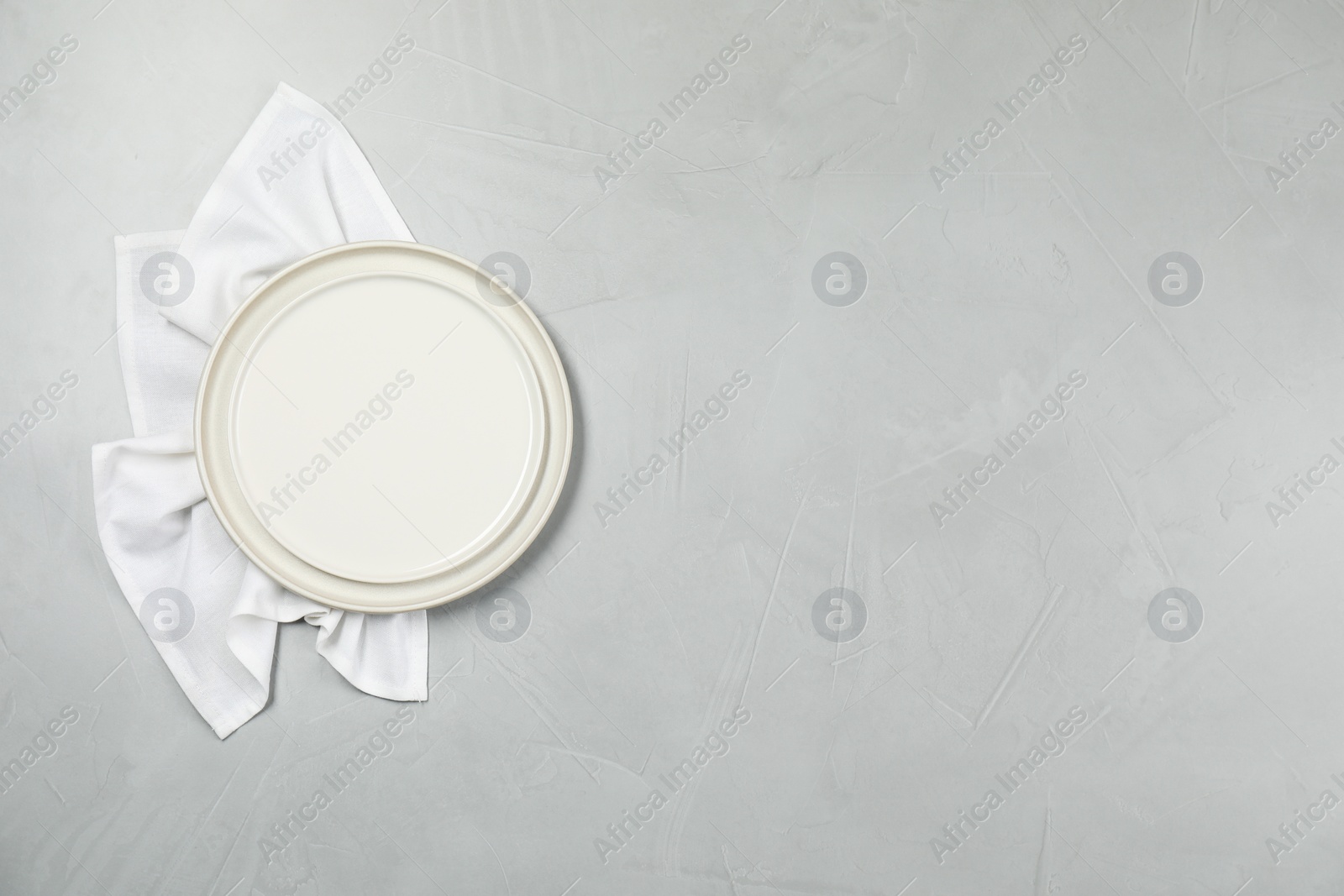 Photo of Elegant plate and napkin on grey table, top view. Space for text