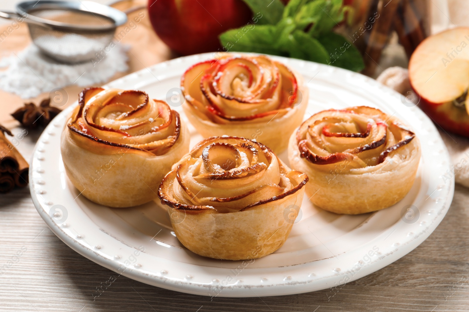 Photo of Freshly baked apple roses on white wooden table. Beautiful dessert