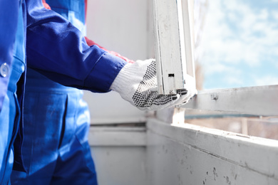 Photo of Workers dismantling old window indoors, closeup view