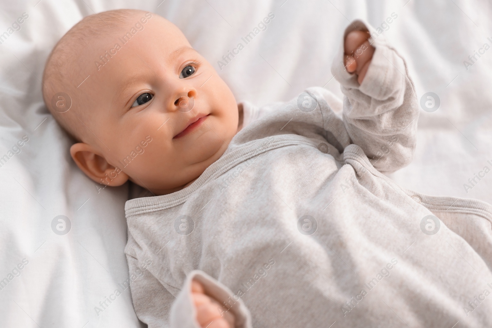 Photo of Cute little baby lying on white sheets