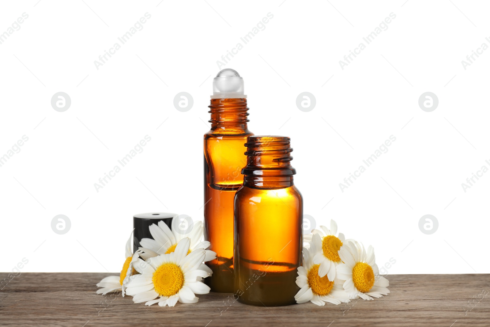 Photo of Bottles of chamomile essential oil and flowers on wooden table, white background