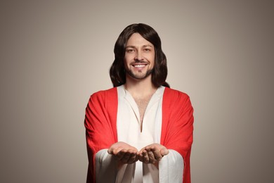 Photo of Jesus Christ reaching out his hands on beige background