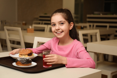 Photo of Little girl with tasty food at table in school canteen