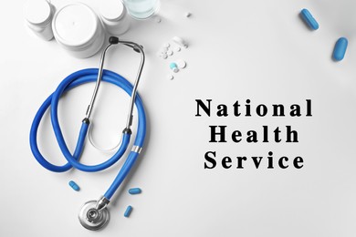 National health service (NHS). Stethoscope, pills and text on white background, top view