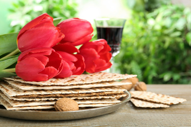 Photo of Traditional Matzos and tulips on wooden table. Pesach (Passover) celebration