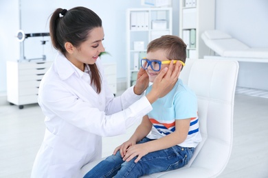 Photo of Children's doctor putting glasses on little boy in clinic