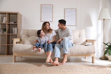 Photo of Happy family with little daughter sitting on sofa in living room