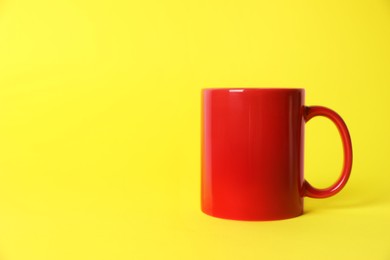 Photo of One red ceramic mug on yellow background. Space for text