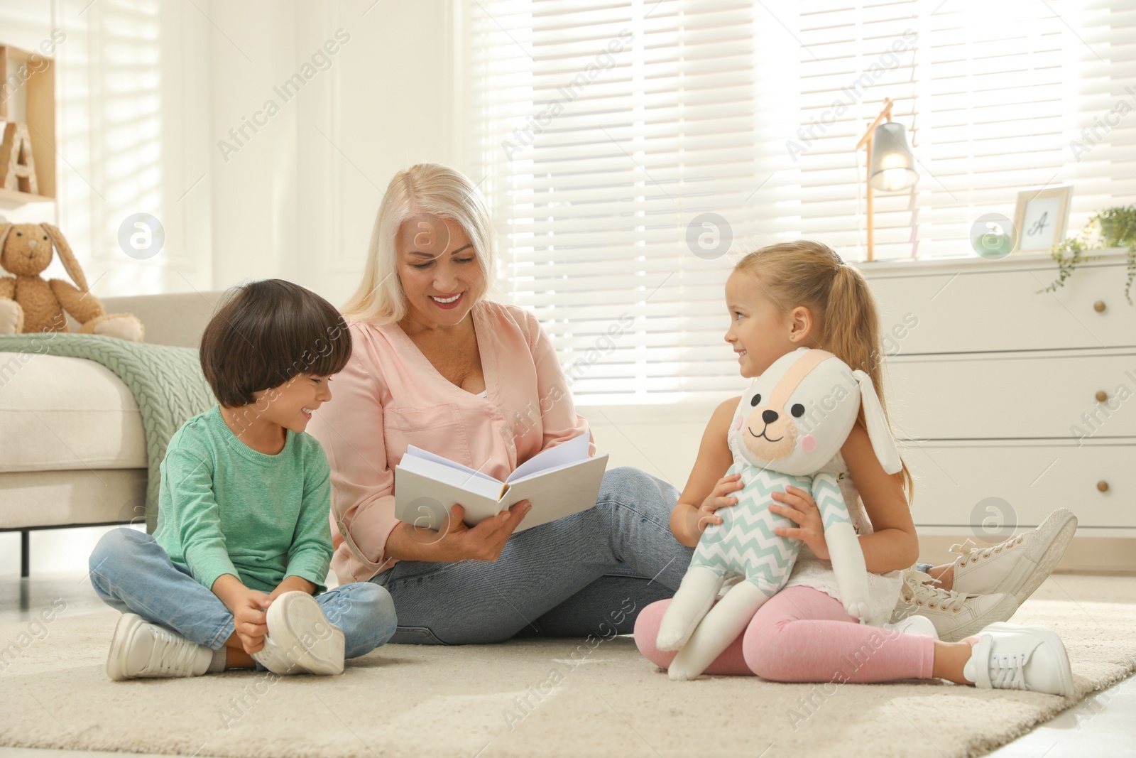 Photo of Happy grandmother and her grandchildren spending time together at home