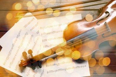 Image of Christmas and New Year music. Violin and music sheets on wooden background, bokeh effect