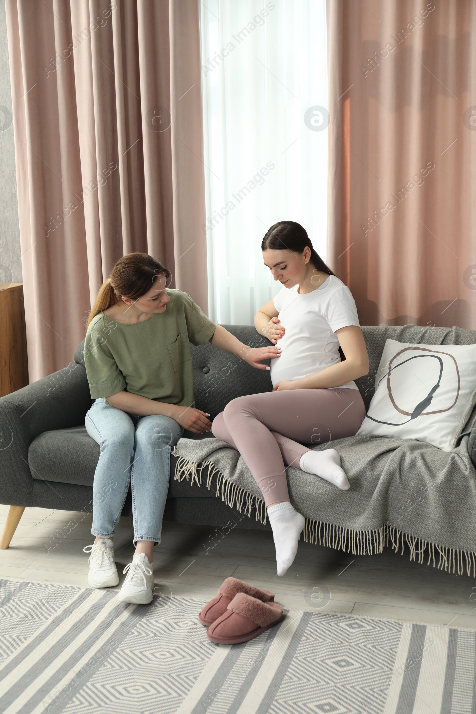 Photo of Doula taking care of pregnant woman on sofa at home. Preparation for child birth