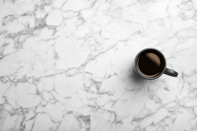 Photo of Ceramic cup with hot aromatic coffee on marble background, top view