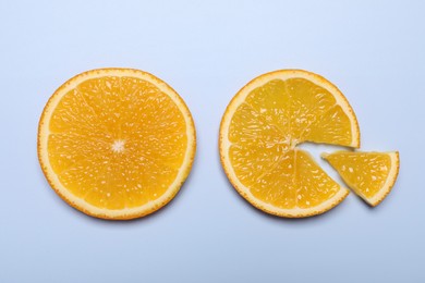 Slices of juicy orange on light blue background, top view