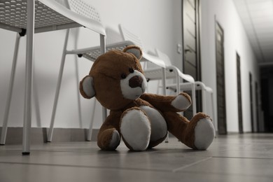 Cute teddy bear left on floor in hallway