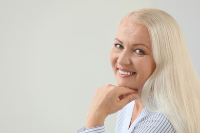 Portrait of beautiful older woman against light background with space for text