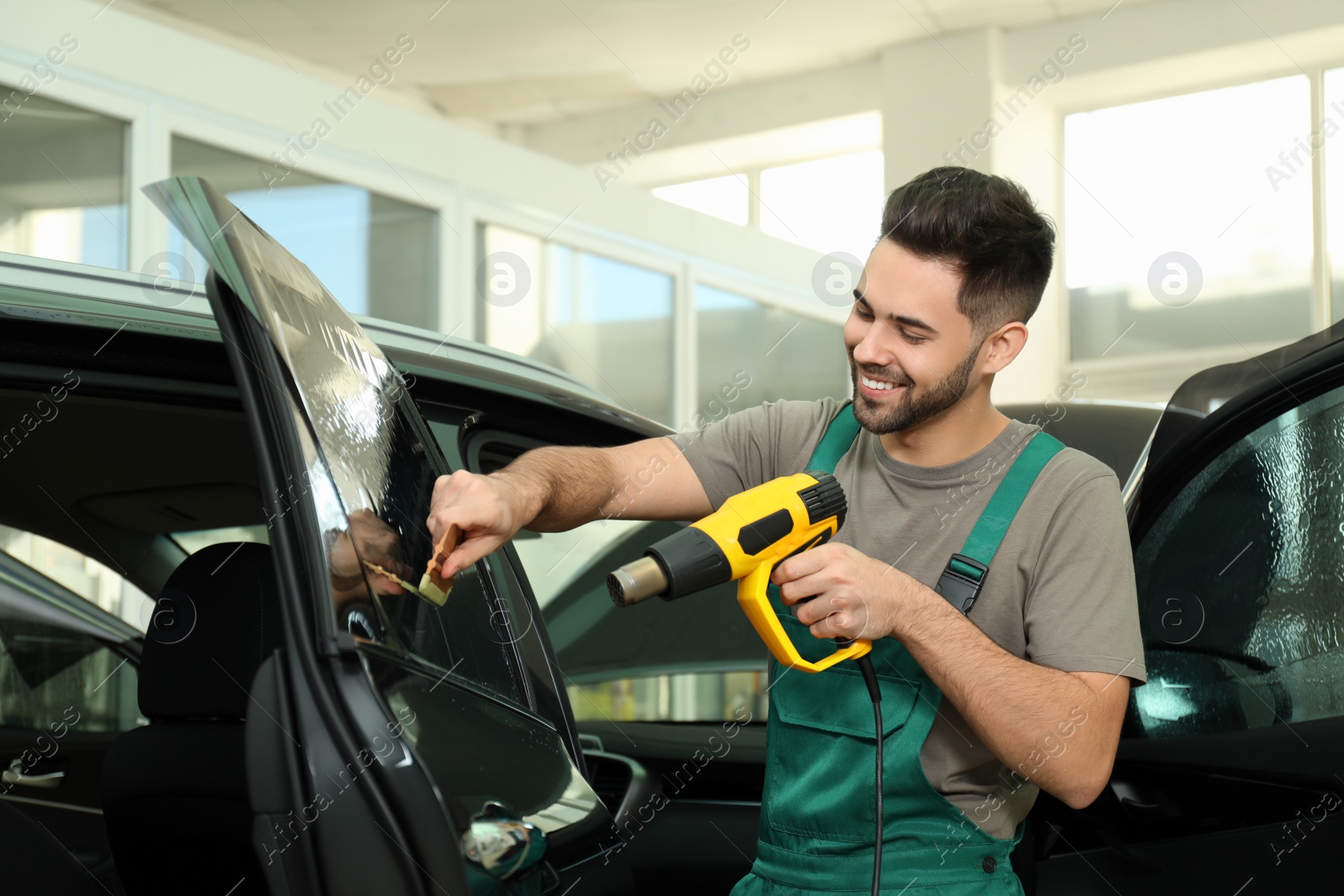 Photo of Worker tinting car window with heat gun in workshop