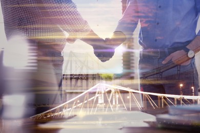 Image of Double exposure of bridge and business partners shaking hands indoors, closeup