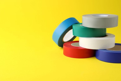 Photo of Colorful insulating tapes on yellow background. Space for text