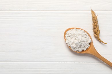 Photo of Spoon of wheat flour on white wooden table, flat lay. Space for text