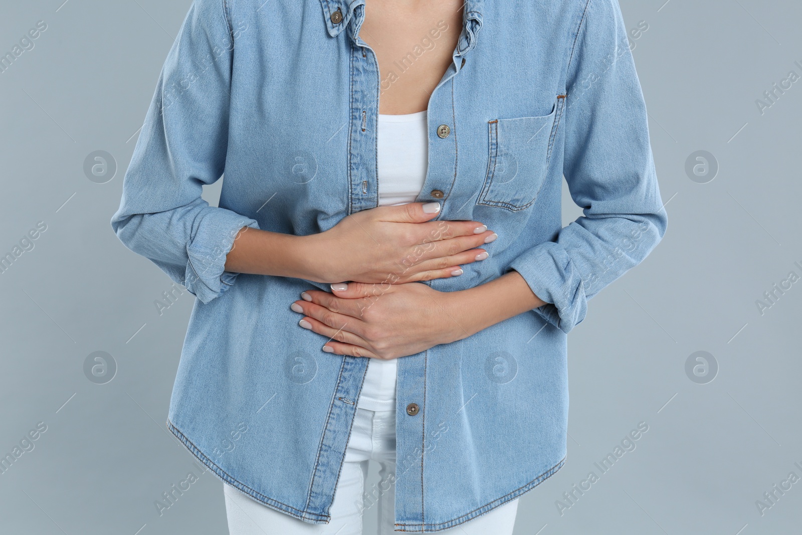 Photo of Woman suffering from stomach ache on grey background, closeup. Food poisoning