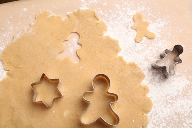 Photo of Making Christmas cookies. Raw dough and cutters of different shapes on parchment paper, flat lay