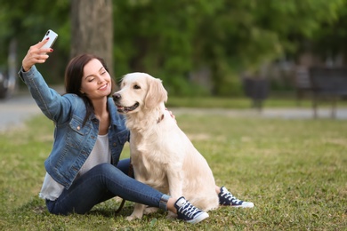 Photo of Young woman taking selfie together with her dog in park. Pet care