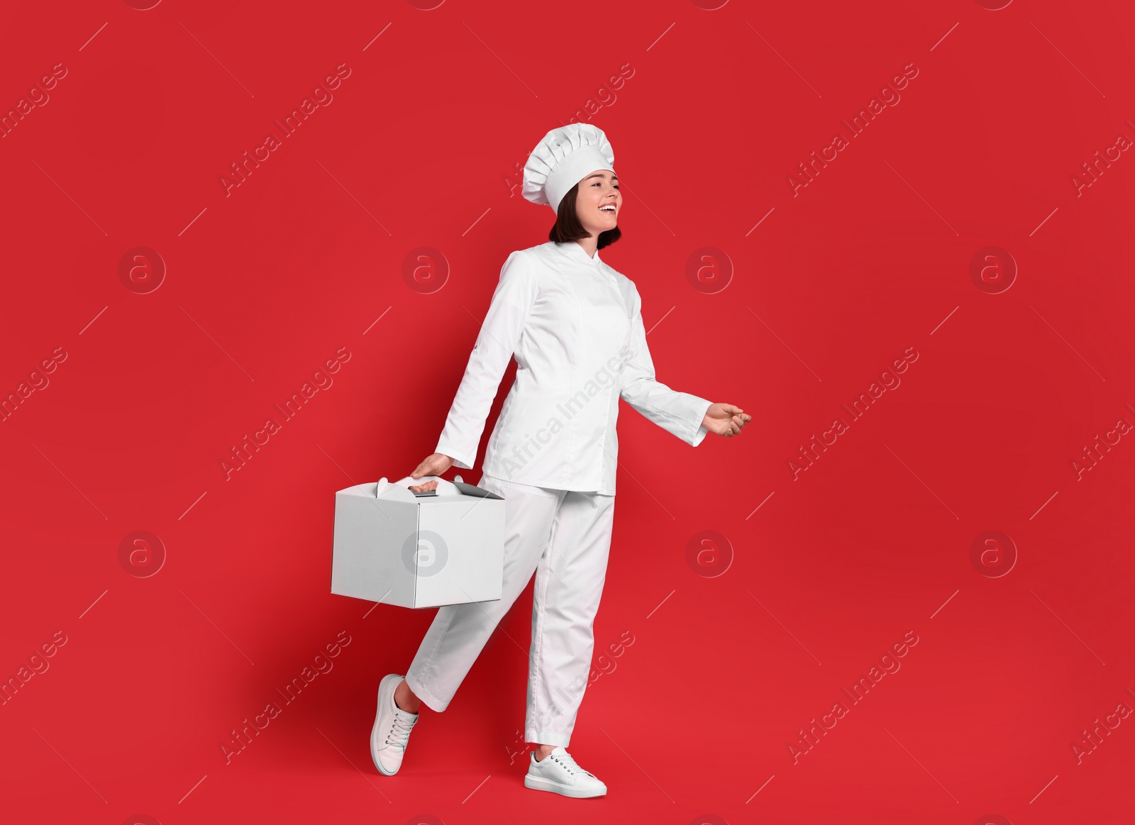 Photo of Happy confectioner with cake box on red background