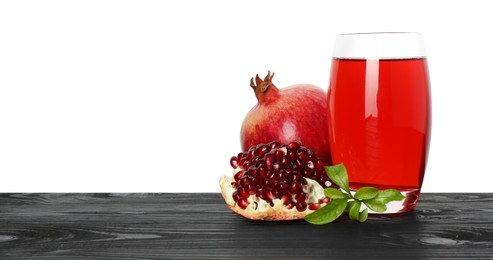 Photo of Refreshing pomegranate juice in glass, leaves and fruits on black wooden table against white background. Space for text
