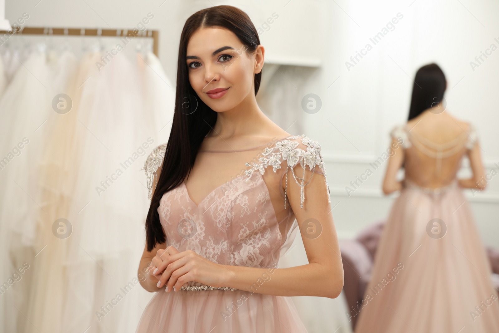 Photo of Woman trying on beautiful wedding dress in boutique