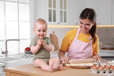 Photo of Happy young woman and her cute baby cooking together in kitchen