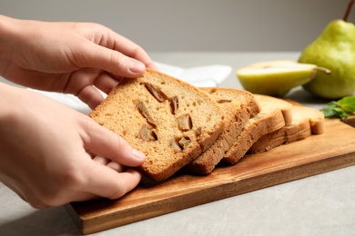 Woman with slice of pear bread at light grey table, closeup. Homemade cake