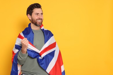 Man with flag of United Kingdom on yellow background, space for text