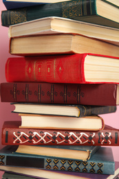 Stack of different hardcover books on pink background