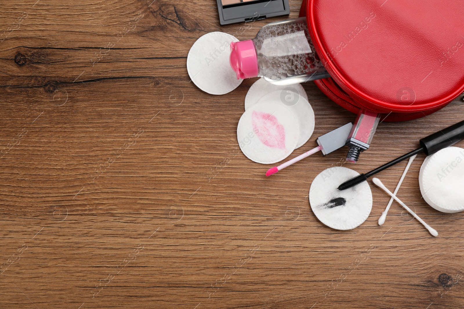 Photo of Dirty cotton pads, swabs, cosmetic products and micellar cleansing water on wooden background, flat lay. Space for text