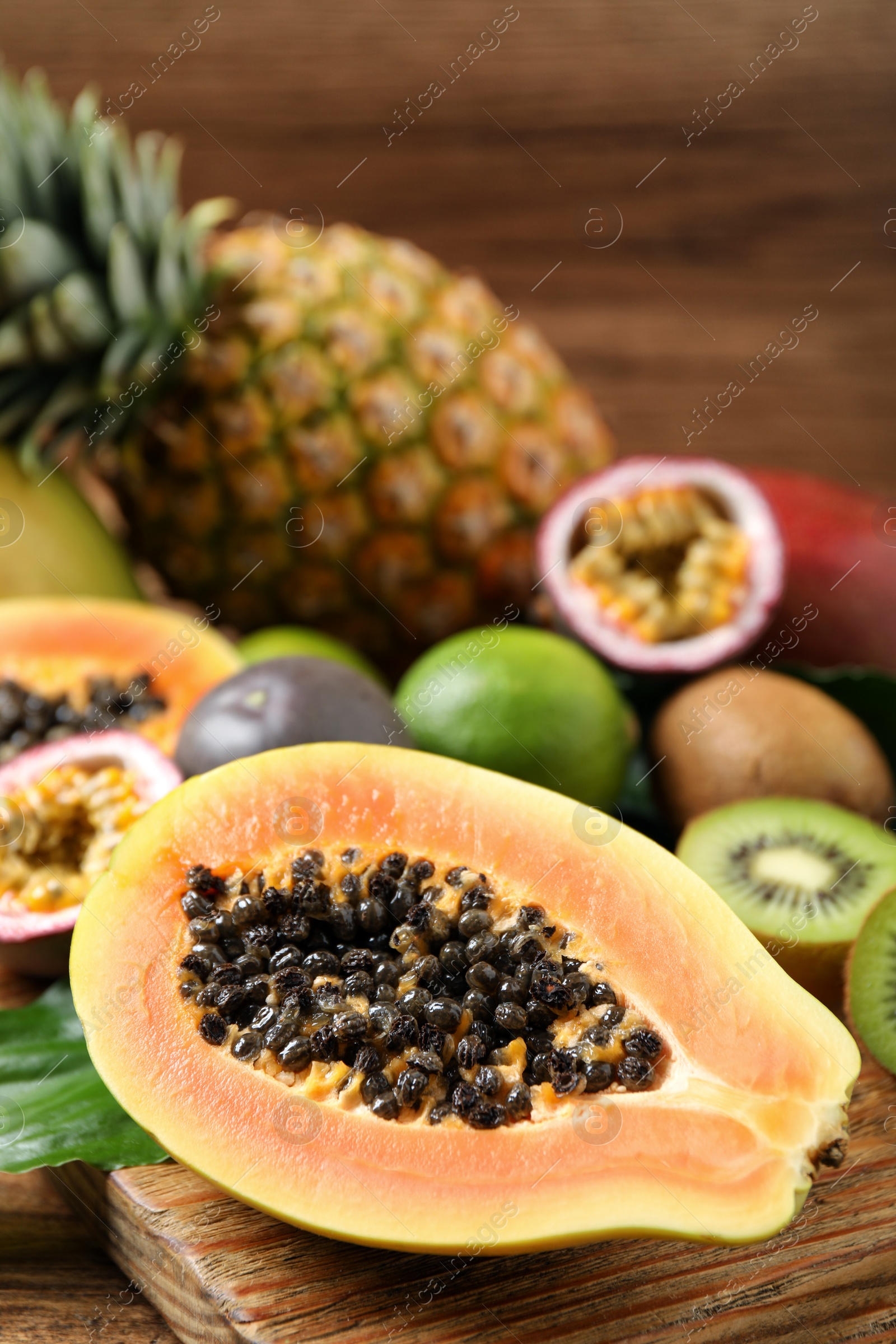 Photo of Fresh ripe papaya and other fruits on wooden table