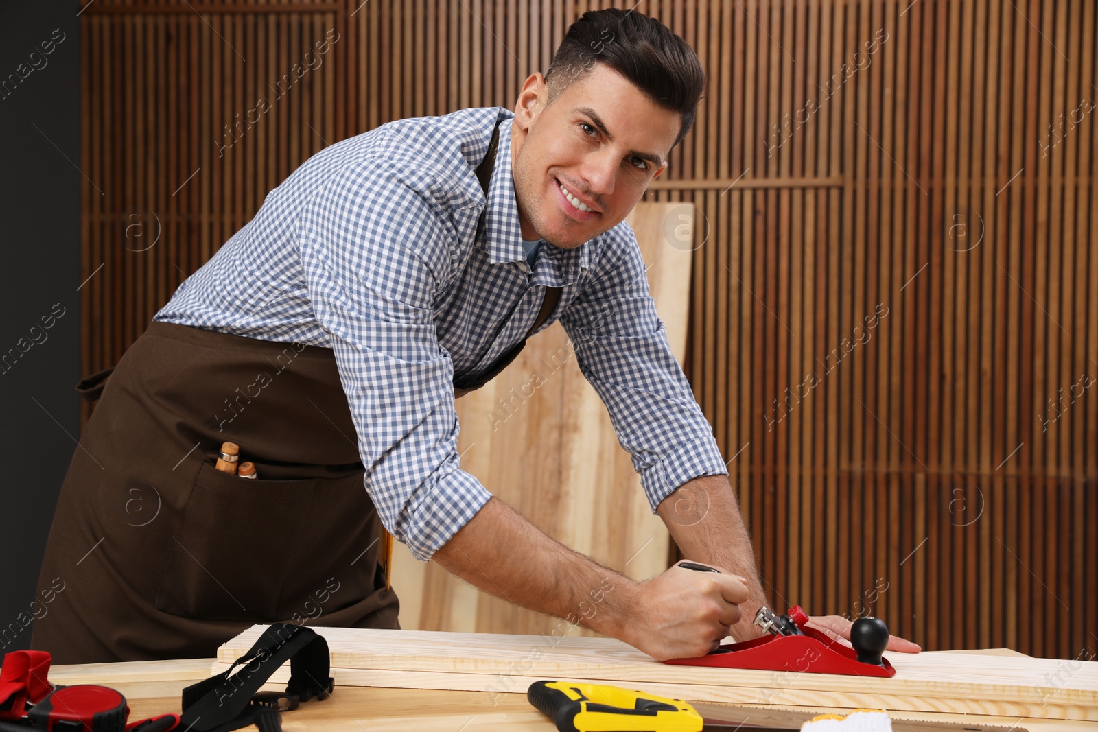 Photo of Handsome carpenter working with timber at table indoors