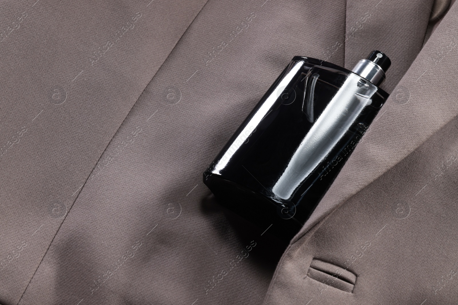 Photo of Luxury men's perfume in bottle on beige jacket, space for text