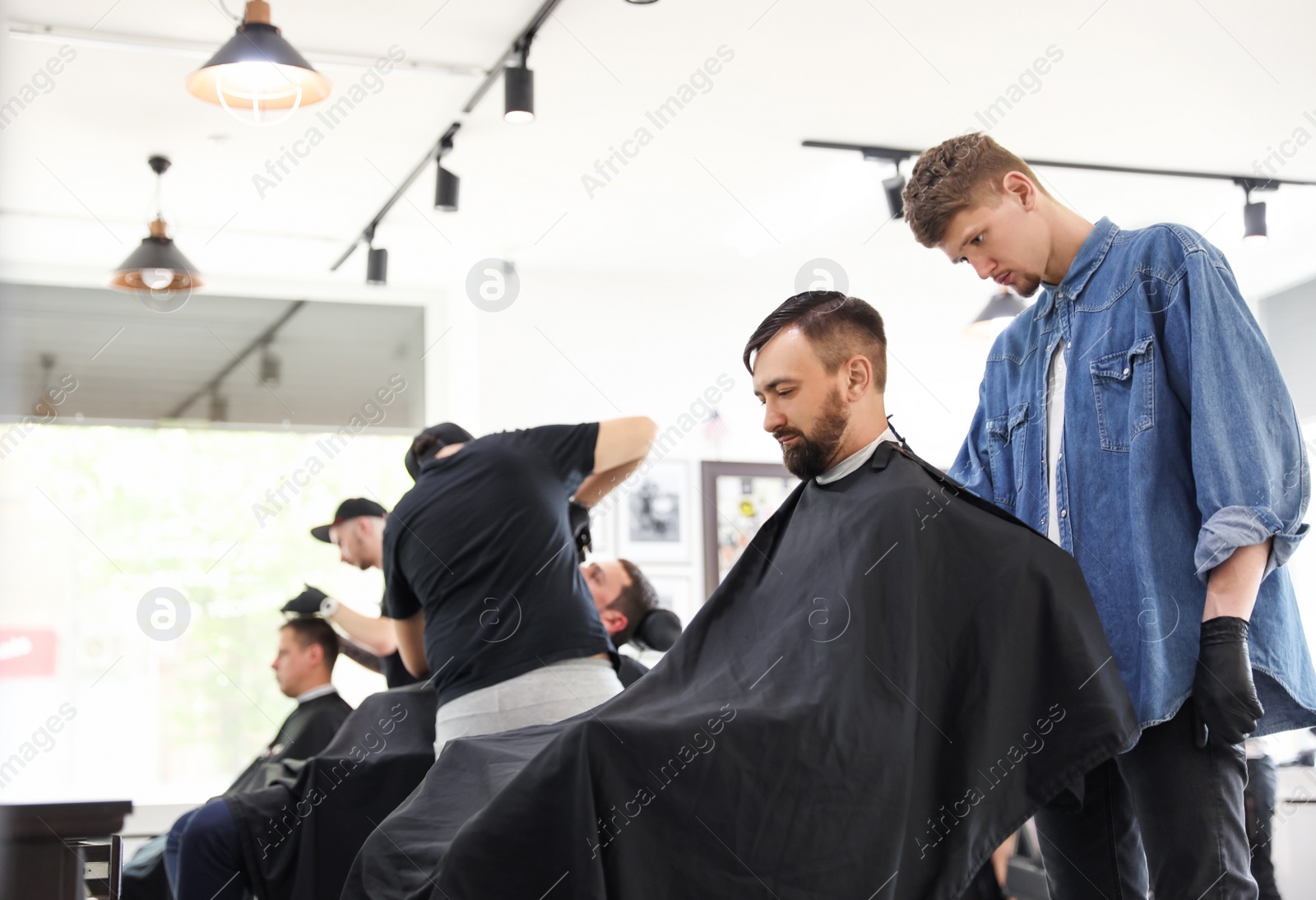 Photo of Professional barber working with client in hairdressing salon. Hipster fashion