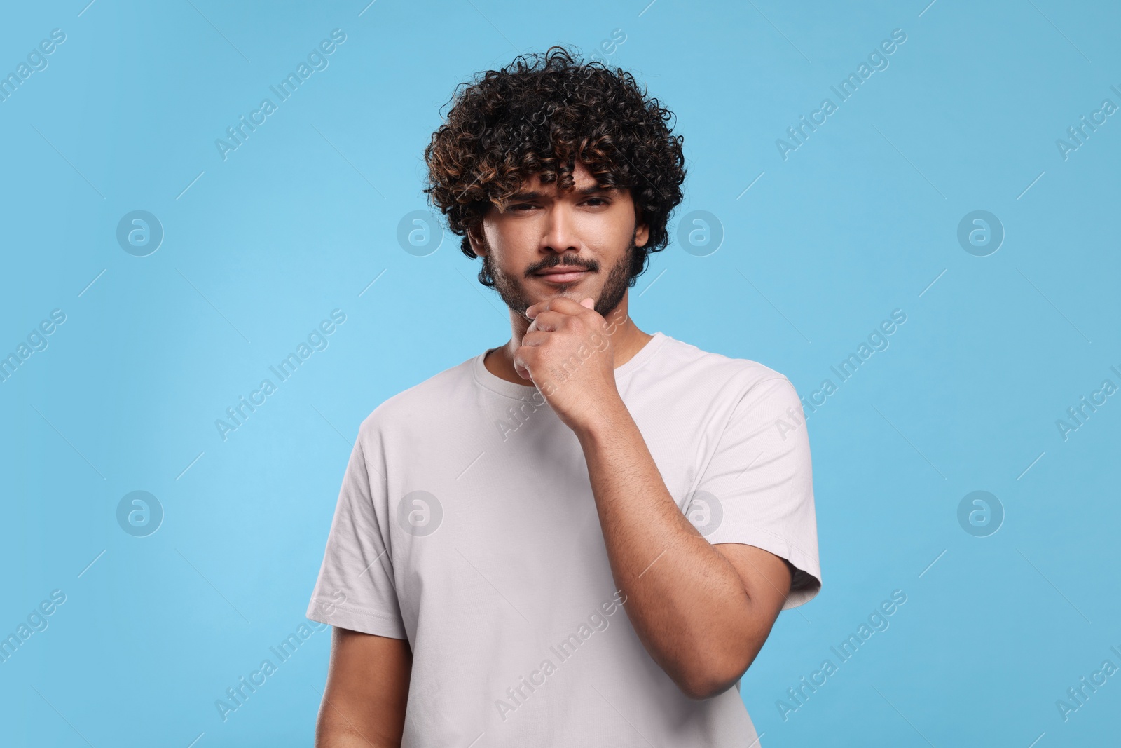 Photo of Handsome thoughtful man on light blue background