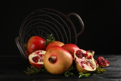 Photo of Delicious ripe pomegranates on black wooden table