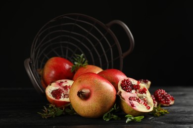 Delicious ripe pomegranates on black wooden table