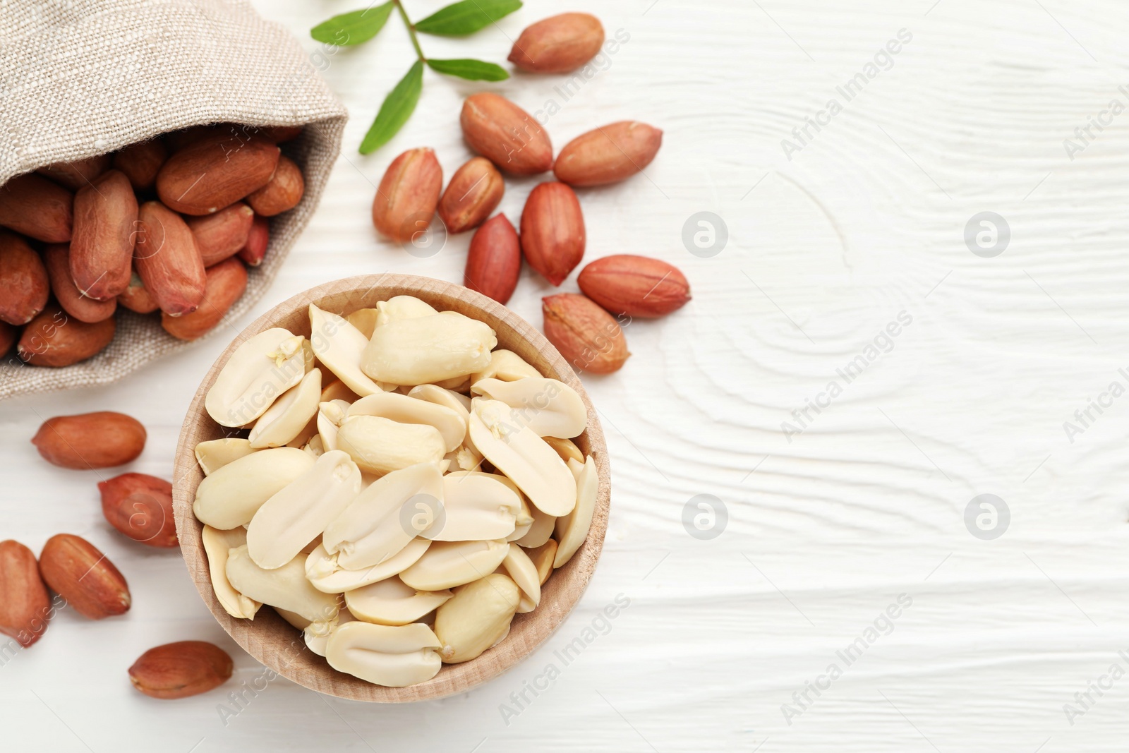 Photo of Fresh peanuts and twig on white wooden table, flat lay. Space for text