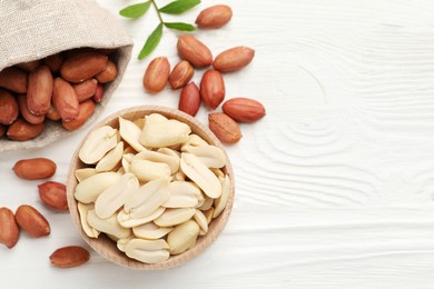 Fresh peanuts and twig on white wooden table, flat lay. Space for text