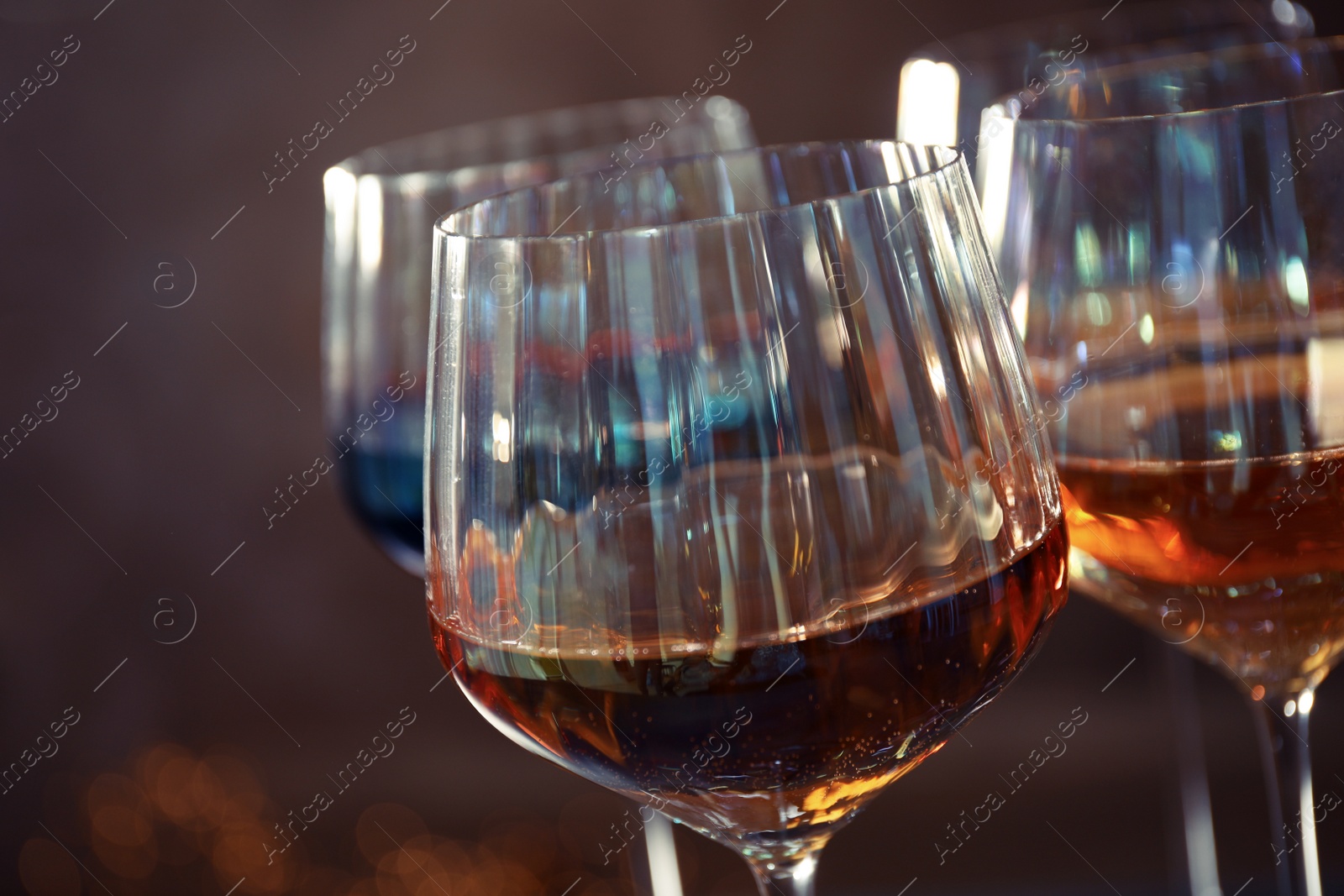 Photo of Elegant glasses with different wines on brown background, closeup