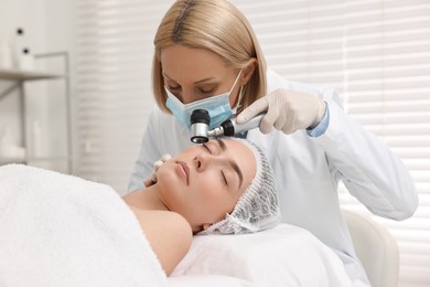 Photo of Dermatologist with dermatoscope examining patient`s face in clinic