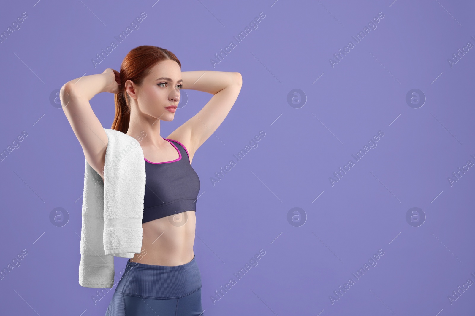 Photo of Woman in sportswear with towel on violet background, space for text