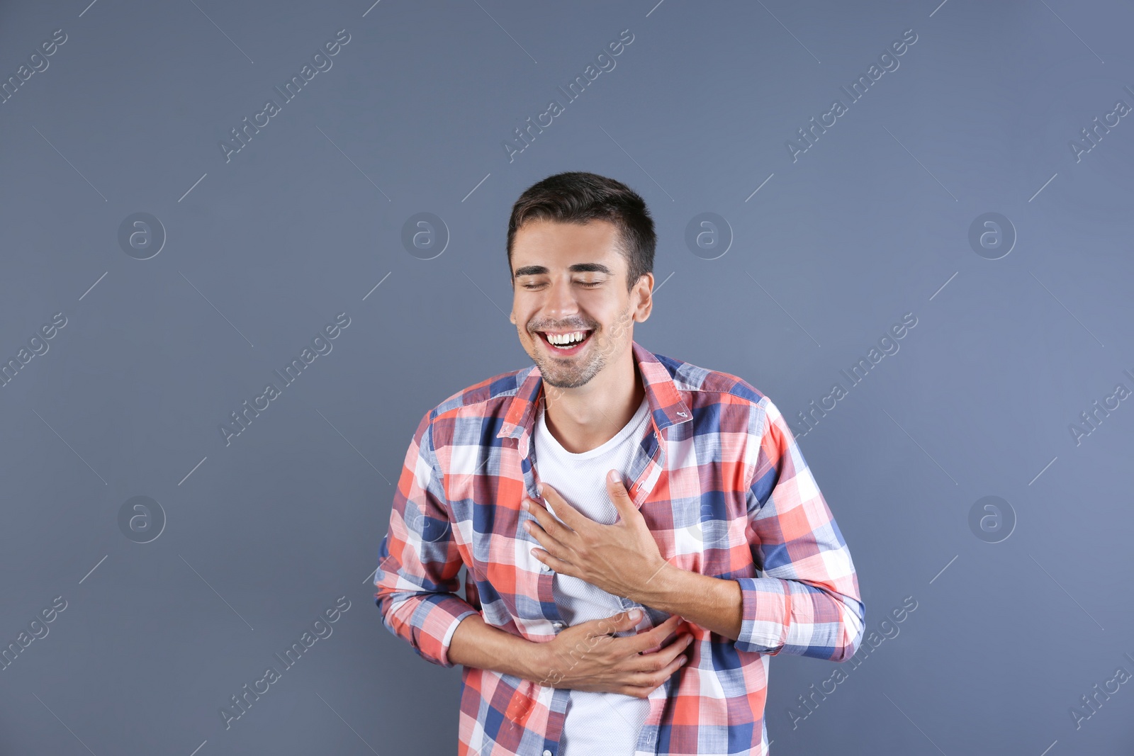 Photo of Portrait of handsome young man laughing on color background